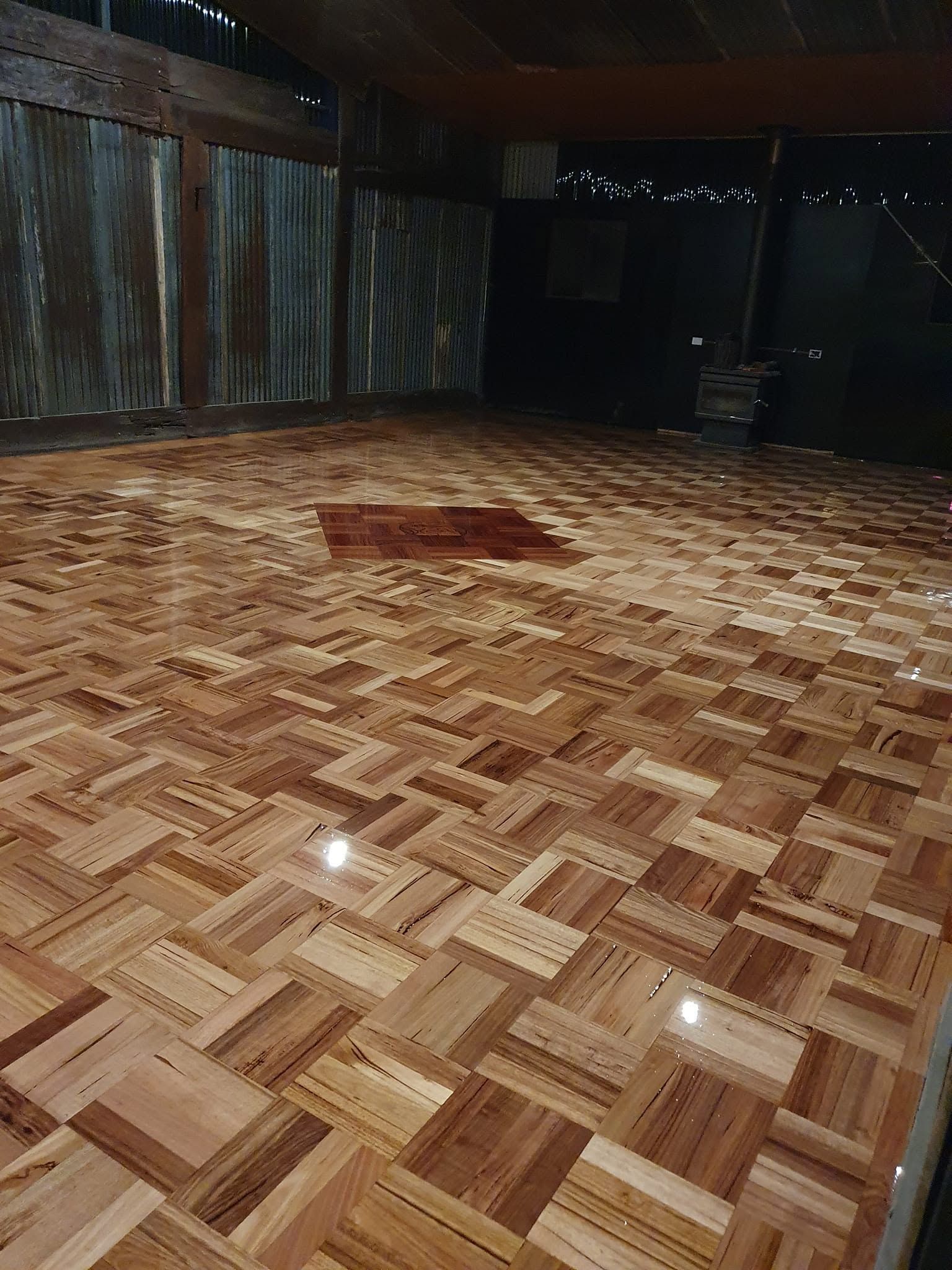 Empty indoor space with shiny parquet floor, wood-paneled walls, and a dark doorway at the back.