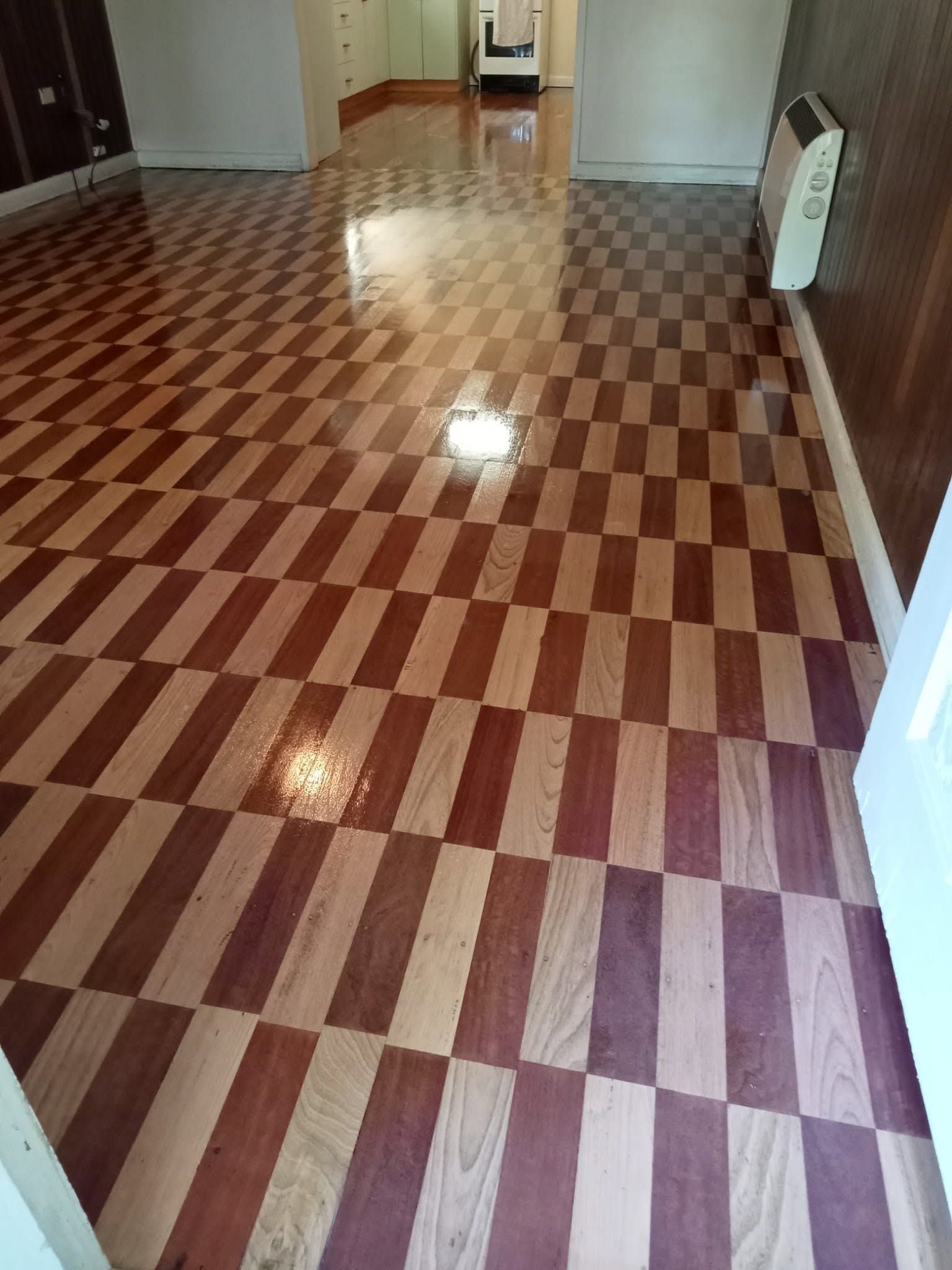 Hallway with glossy red-and-tan checkered floor and white walls, viewed from an open doorway