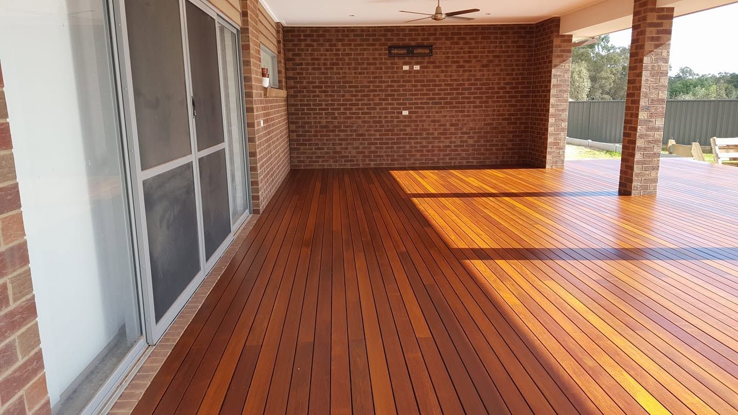 Glossy orange-brown porch floor with sunlight reflections beside white screened walls and windows