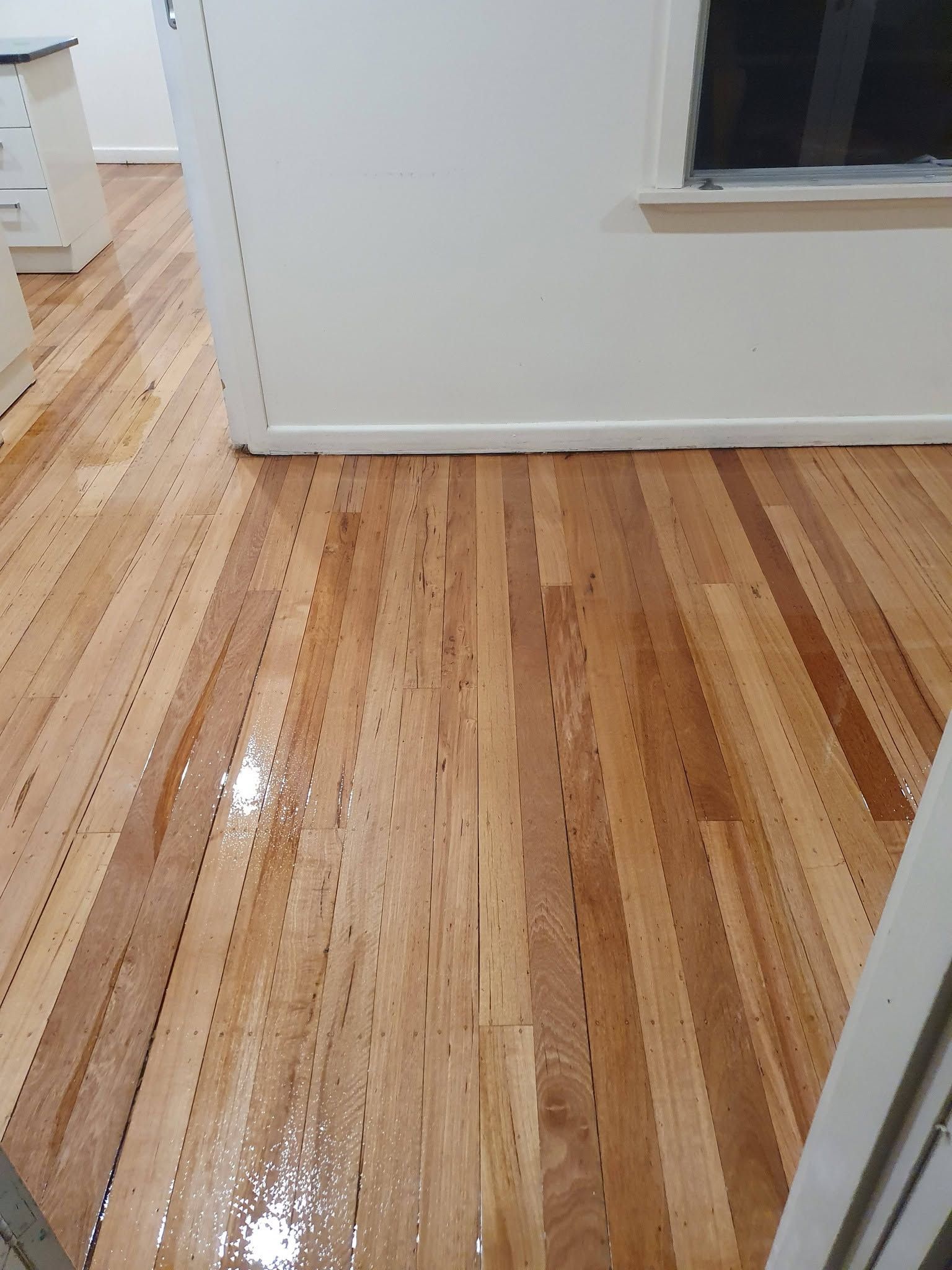 Shiny hardwood floor with light and dark wood planks in a white-walled room
