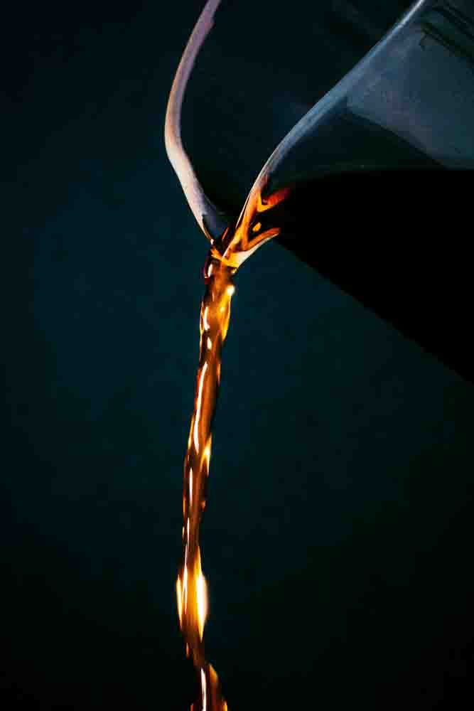 A close up of new motor oil pouring down from a jug
