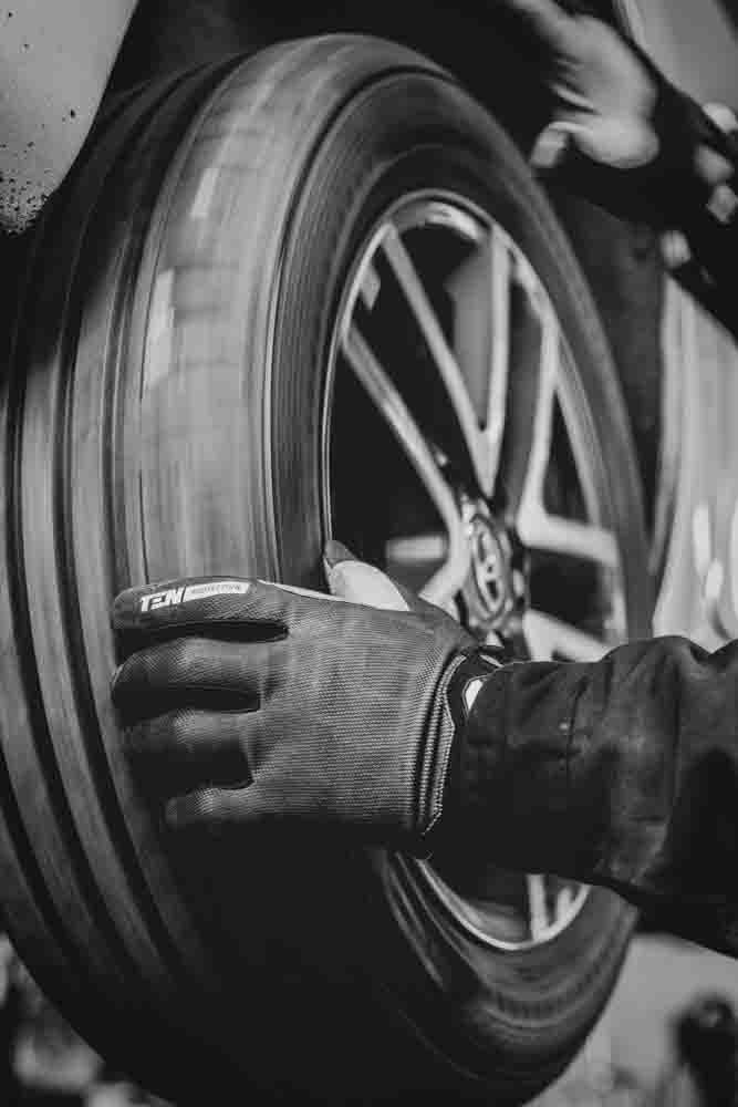 a mobile technician installing a rim, tire, and wheel onto a car