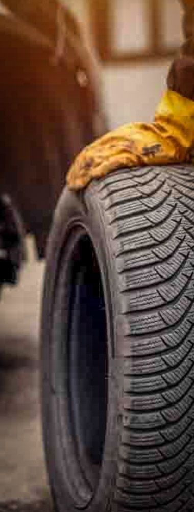 close up of a hand with a yellow rubber glove holding a car tire while doing wheel service