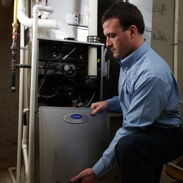 A man in a blue shirt is working on a carrier furnace