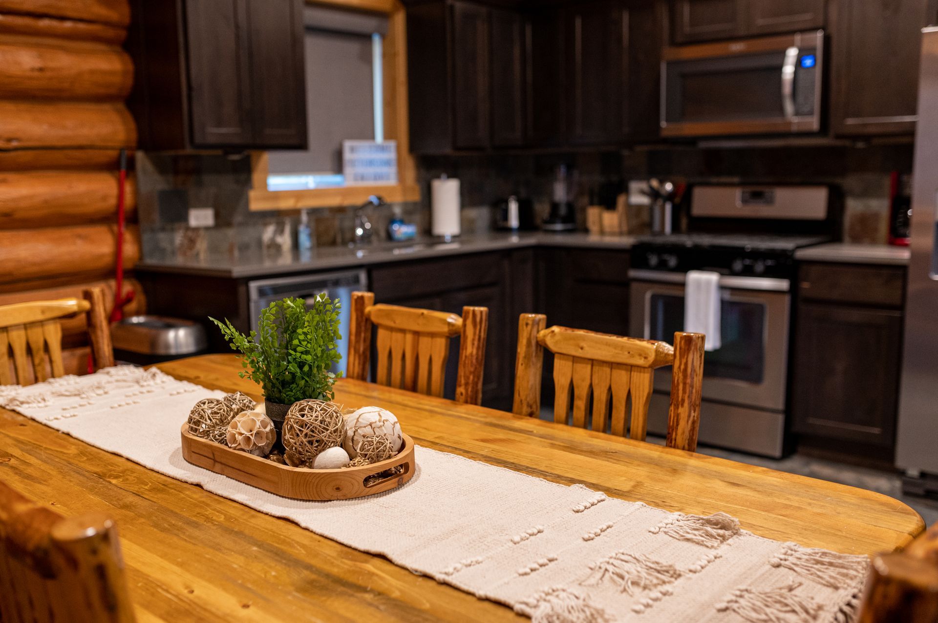 A wooden table and chairs in a kitchen in a log cabin.