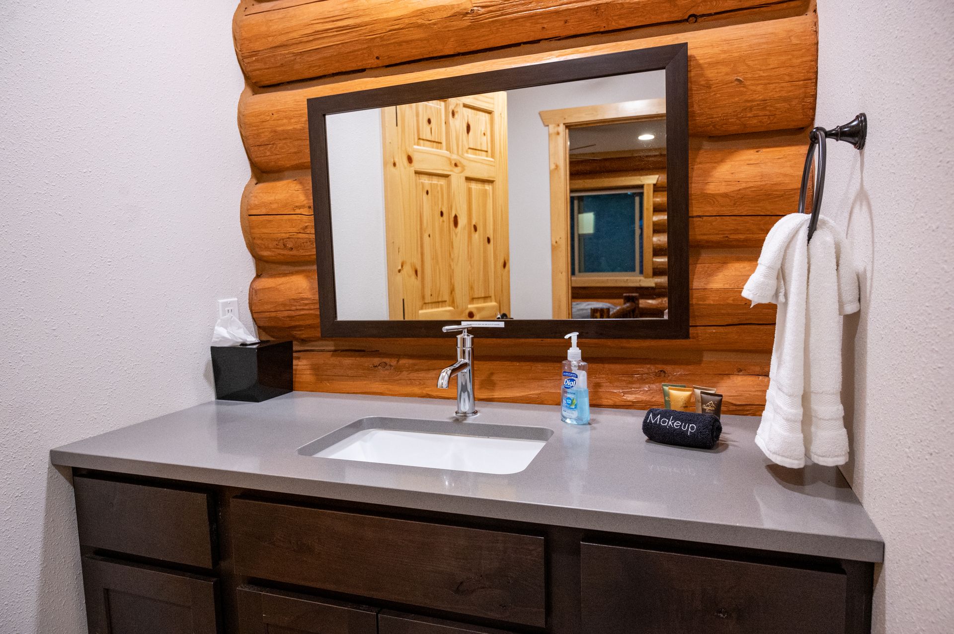 A bathroom in a log cabin with a sink and a mirror.