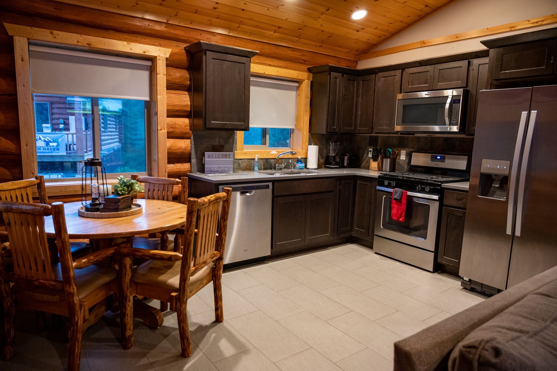 A kitchen in a log cabin with stainless steel appliances and a table and chairs.