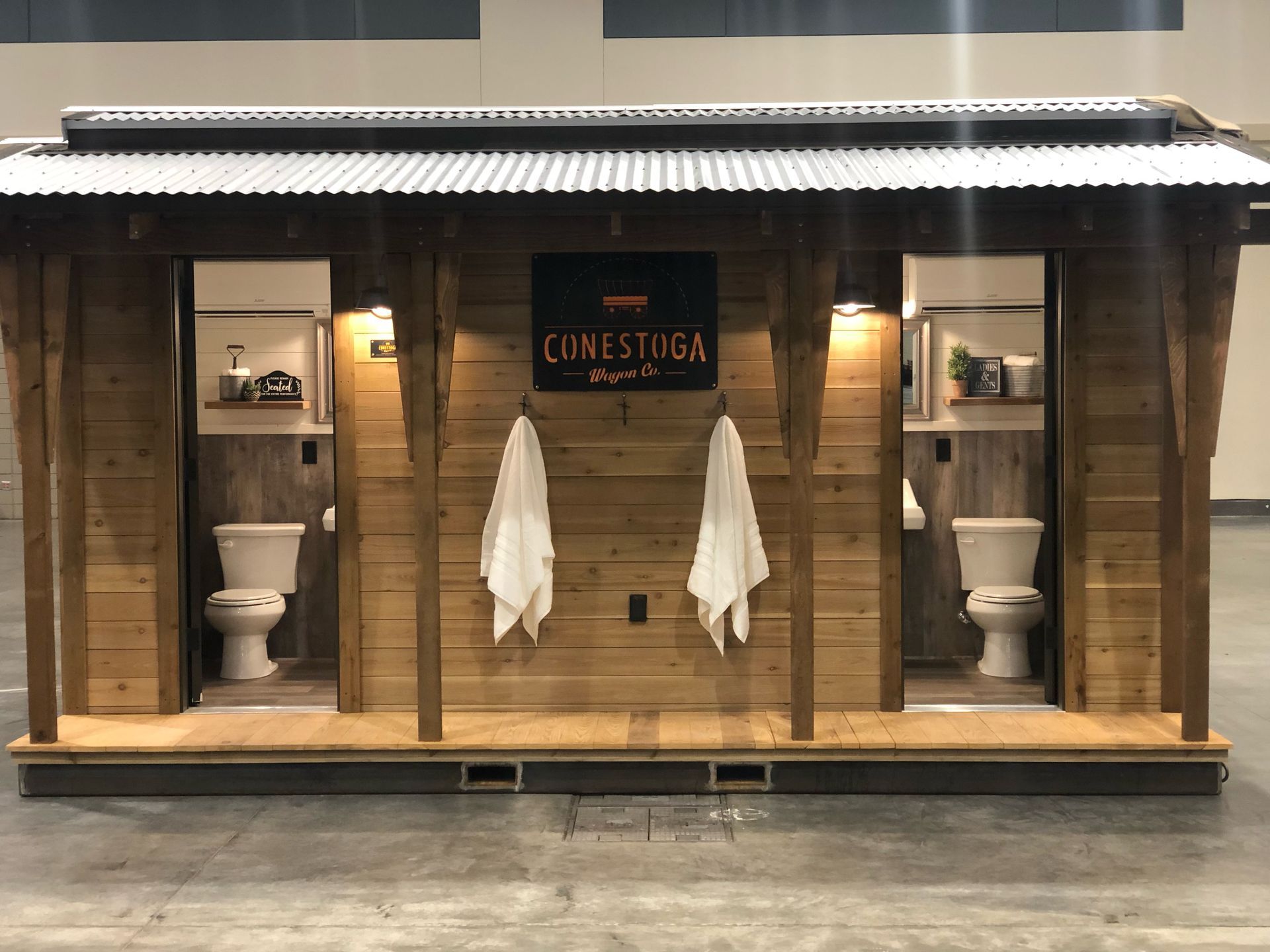 A wooden building with two toilets and two towels hanging on the wall.