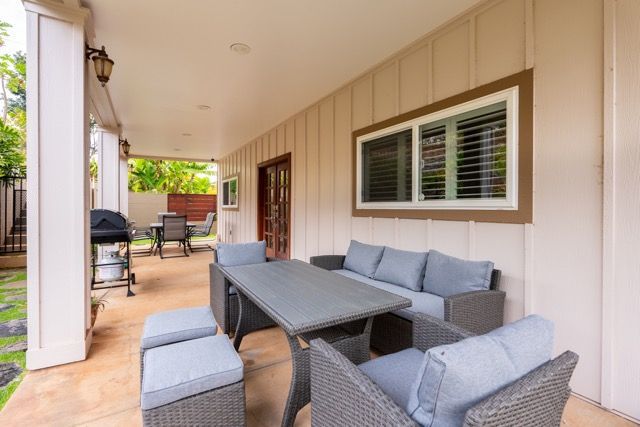 There is a table and chairs on the porch of a house.