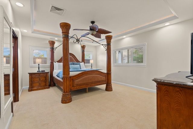 A bedroom with a four poster bed and a ceiling fan.