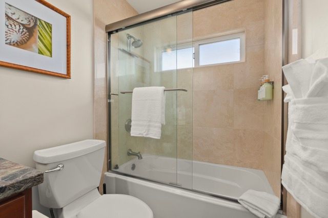 A bathroom with a toilet , tub , shower and picture on the wall.
