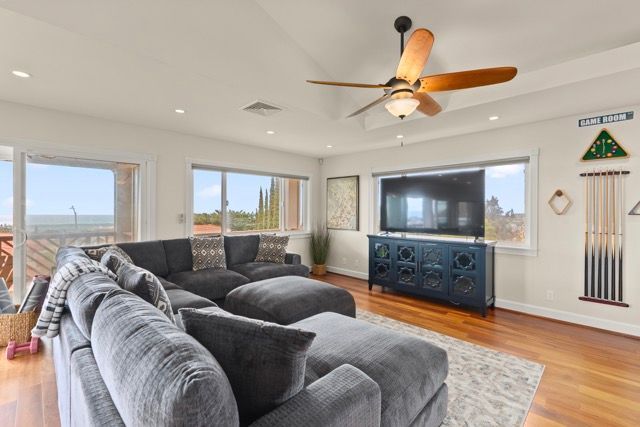 A living room with a couch , chair , television and ceiling fan.