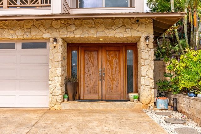 The front of a house with a wooden door and a stone wall.