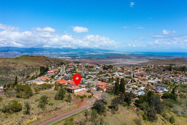 An aerial view of a residential area with a red pin pointing the location of a house.