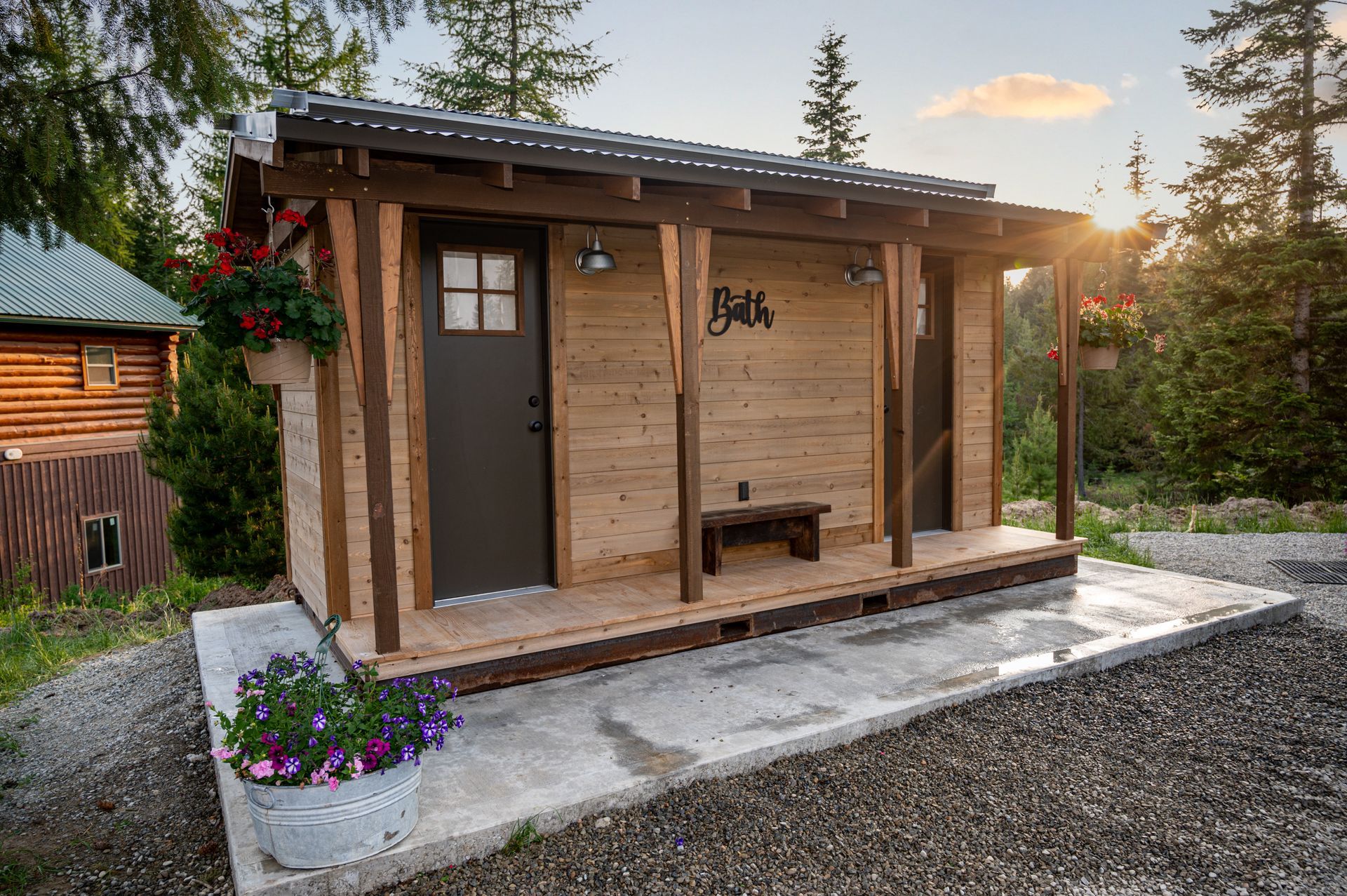 A small wooden cabin with a porch and a bench.