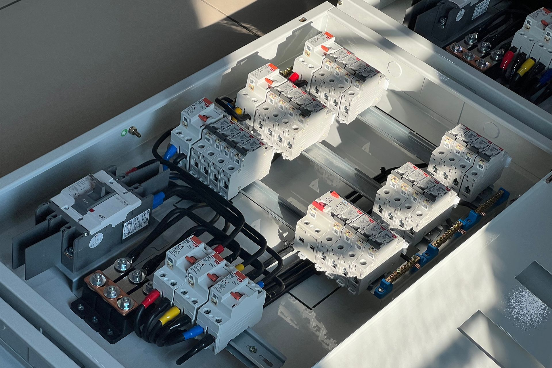 Electrical panel with rows of circuit breakers and wiring under bright light.