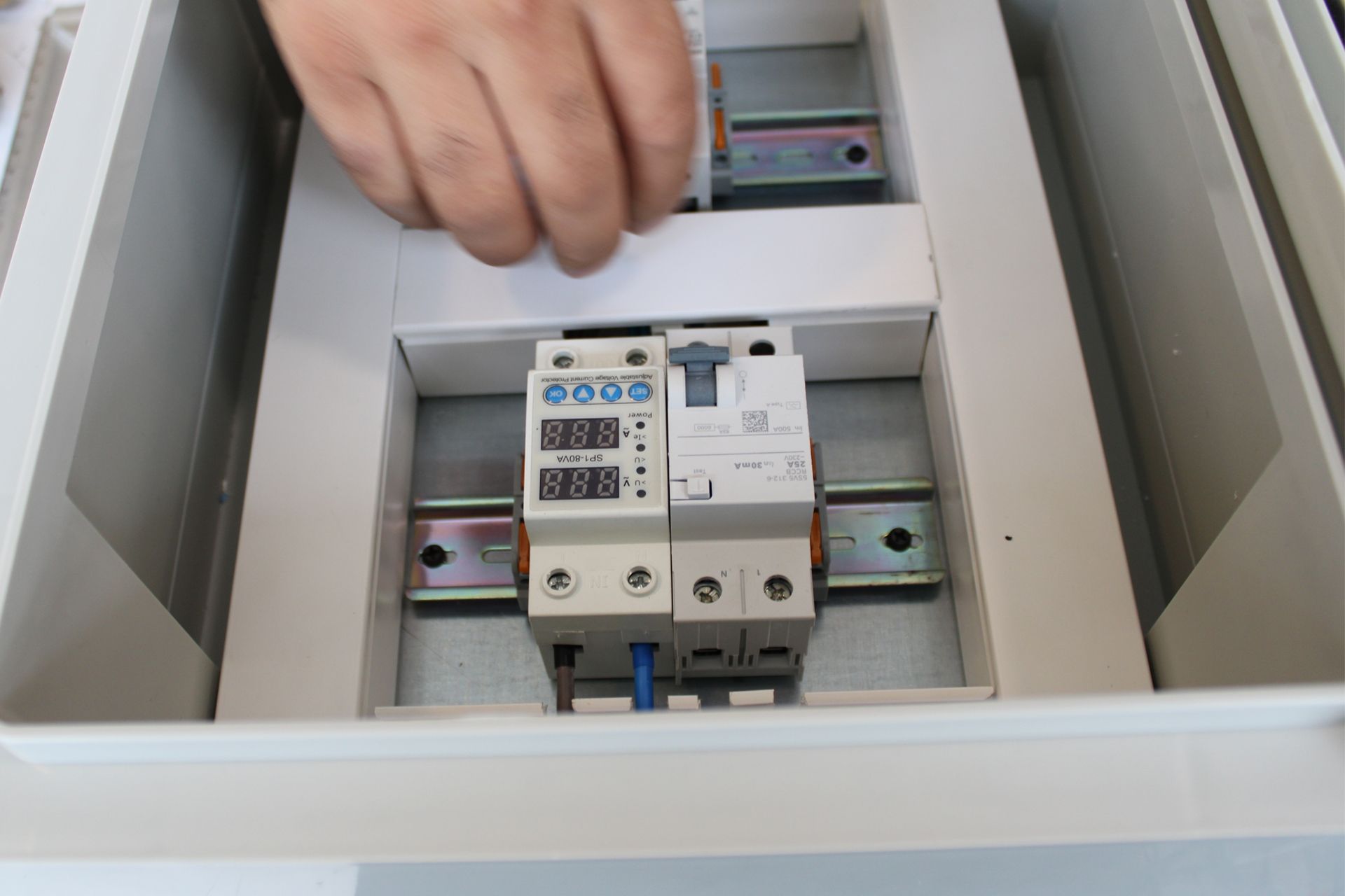 Hand placing a circuit breaker into an electrical panel cabinet.