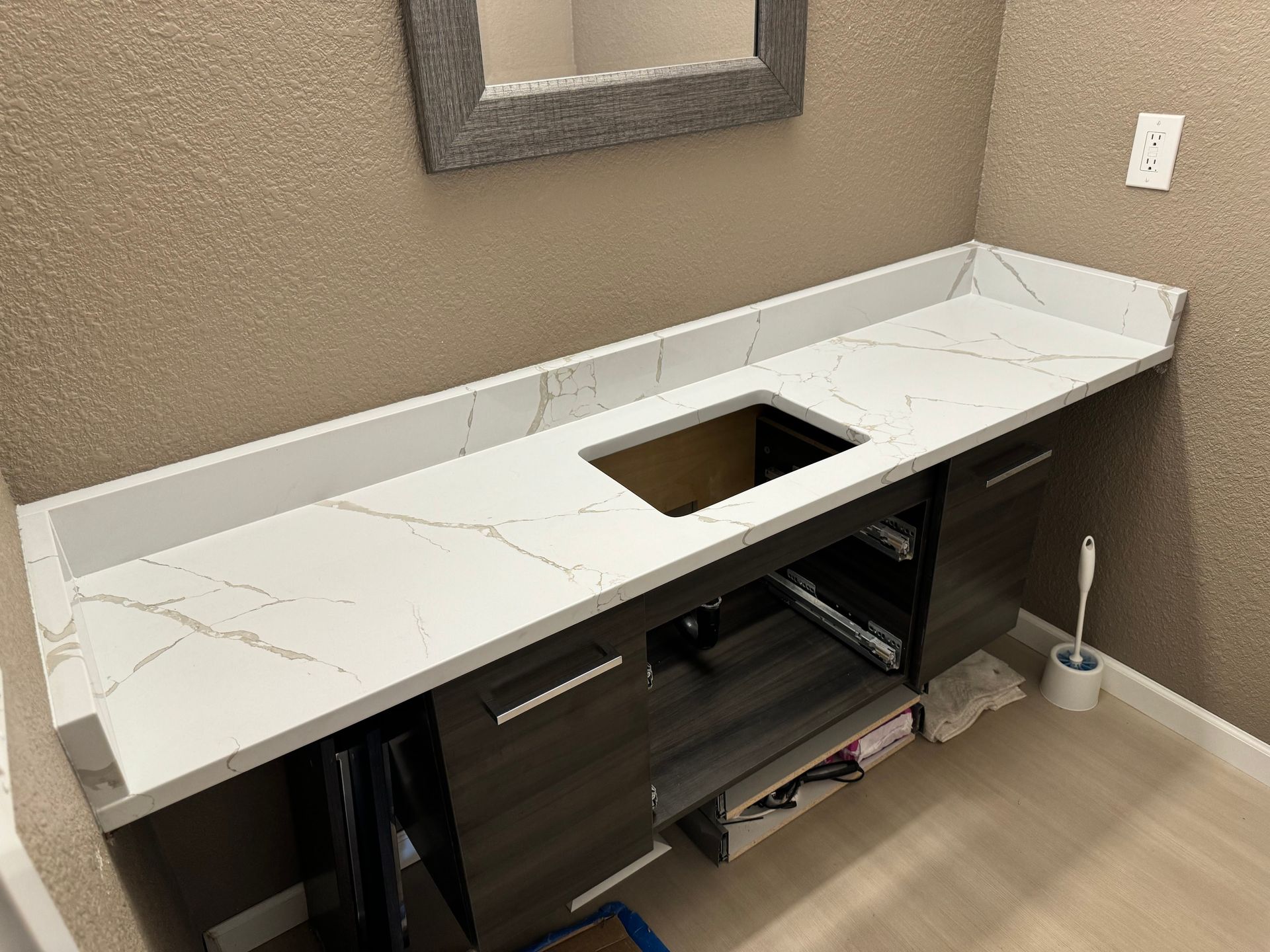 Empty bathroom vanity with white countertop and square sink cutout, under a wall mirror.