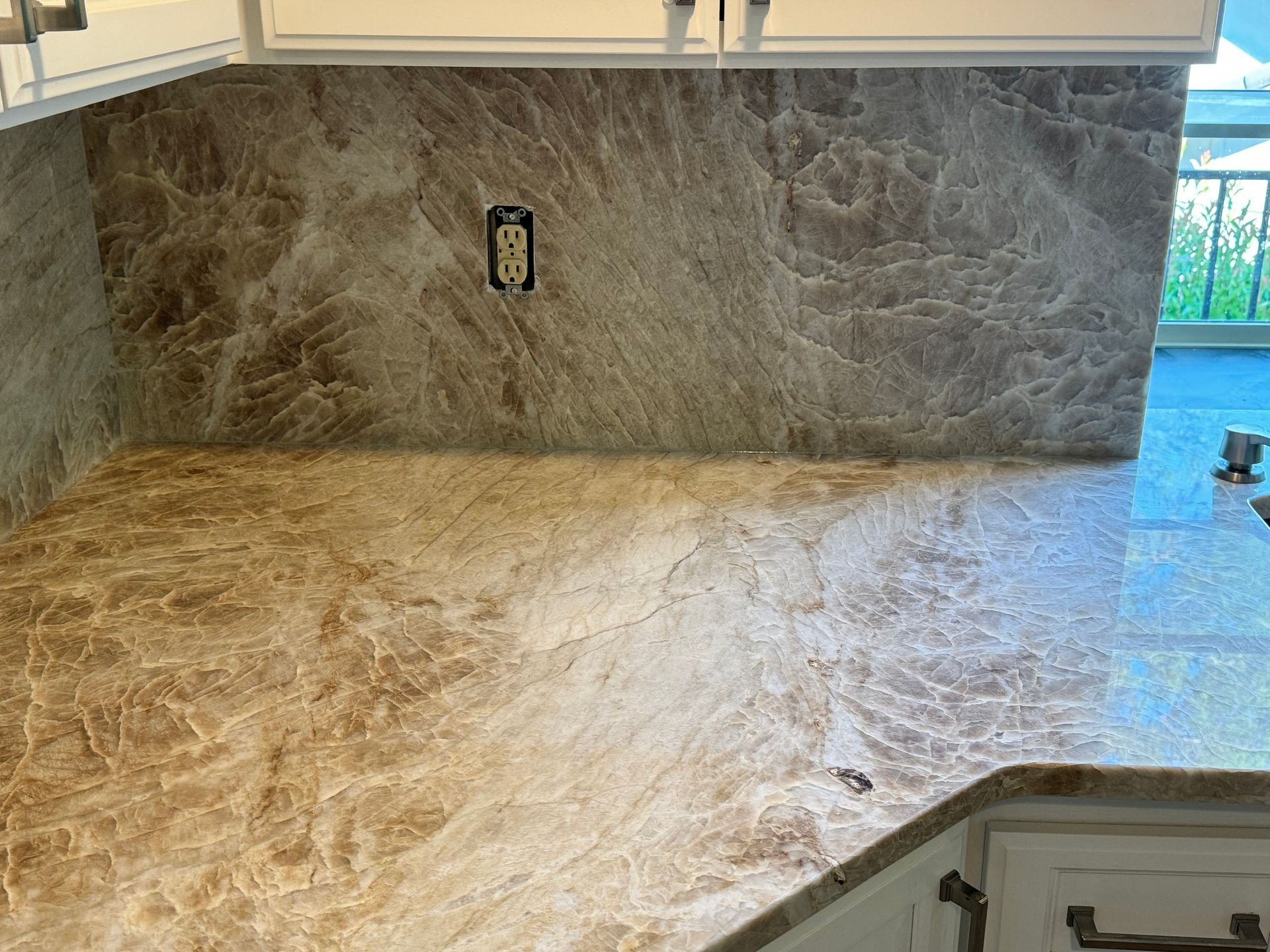 Marble kitchen countertop and backsplash with a corner sink and window light