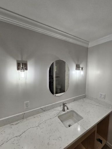 Modern bathroom vanity with oval mirror, wall sconces, and white marble countertop.