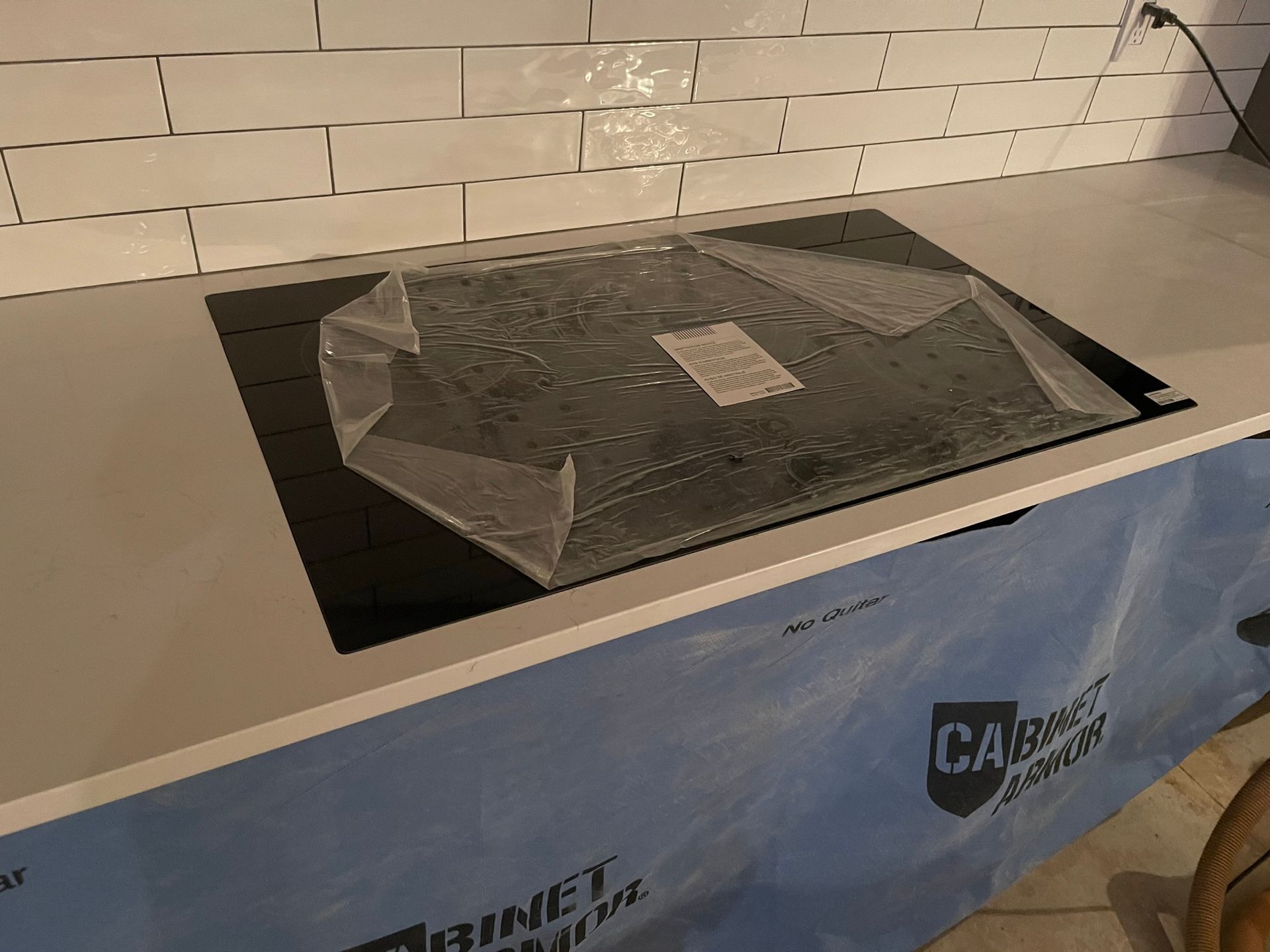 Crumpled black tarp covering a machine display on a blue trade show booth counter, with brick wall backdrop