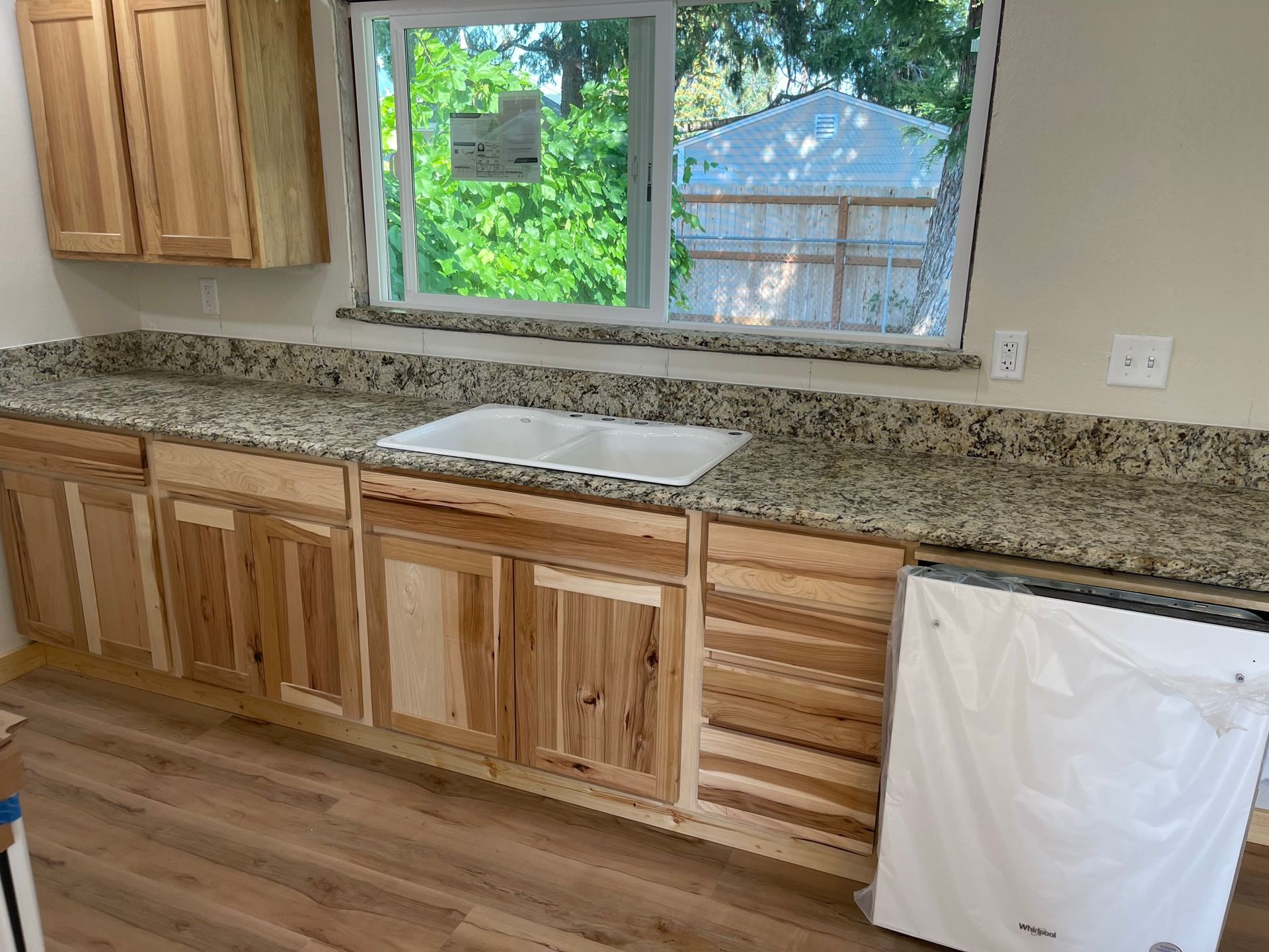Empty kitchen with wooden cabinets, granite countertop, and a window above the sink