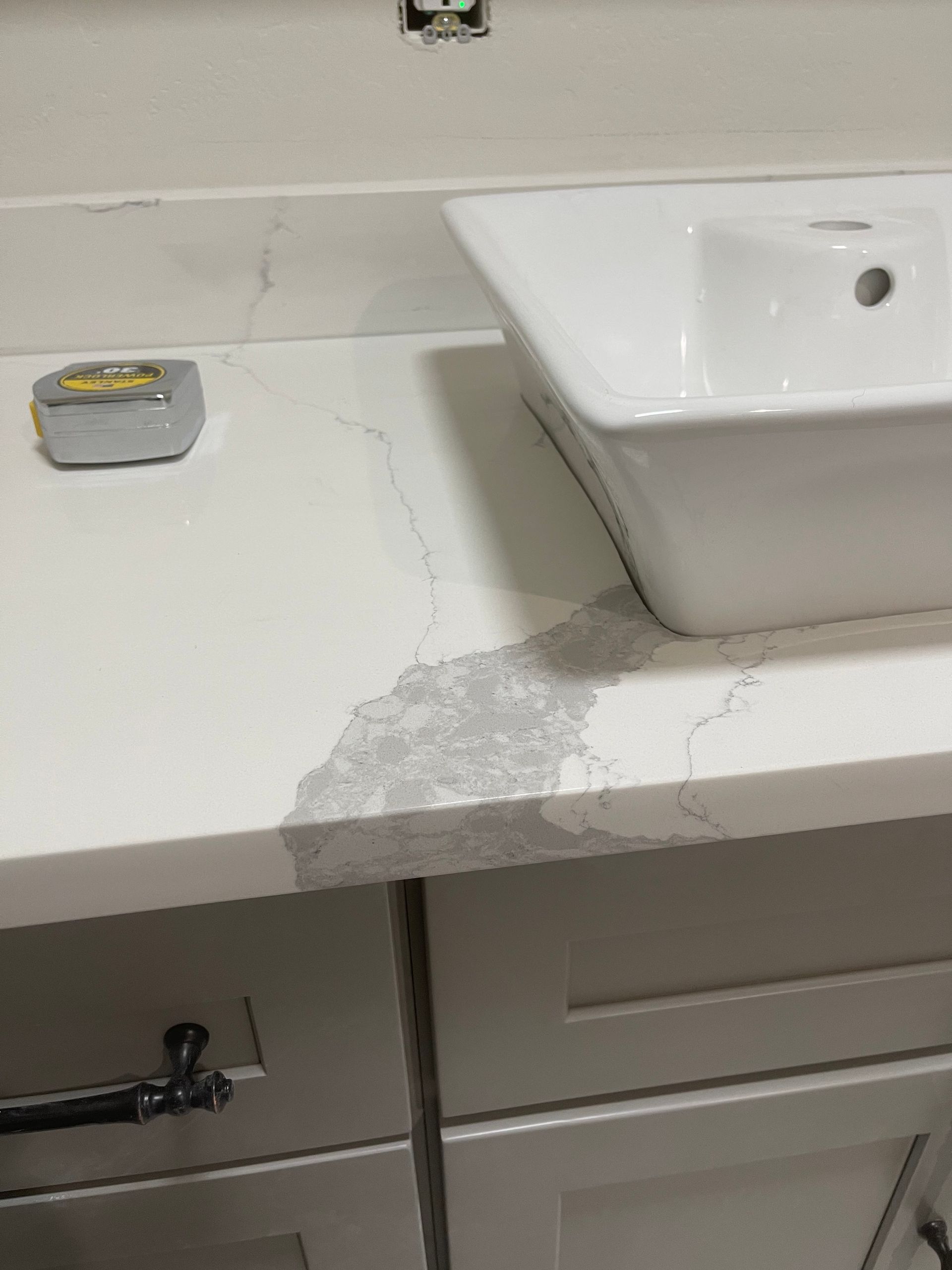Bathroom countertop with chipped paint near a white sink and faucet, showing visible damage and wear.