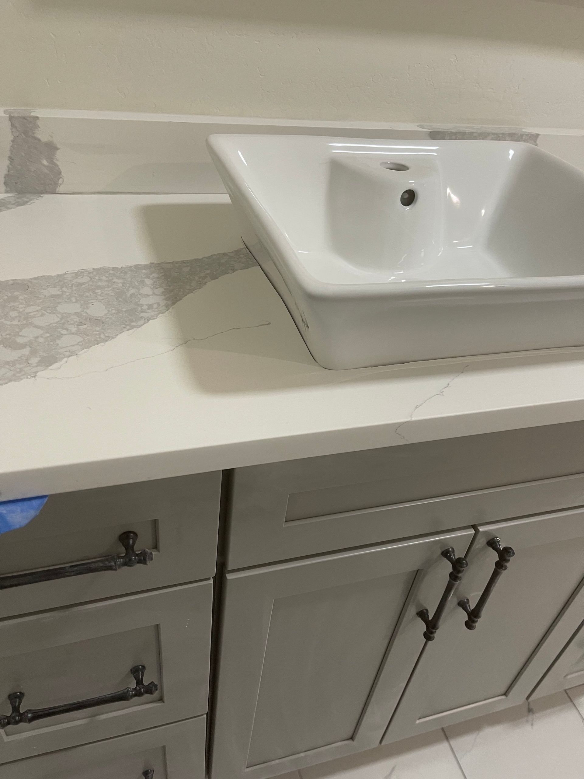 Bathroom vanity with white sink, light countertop, and gray cabinet doors below.