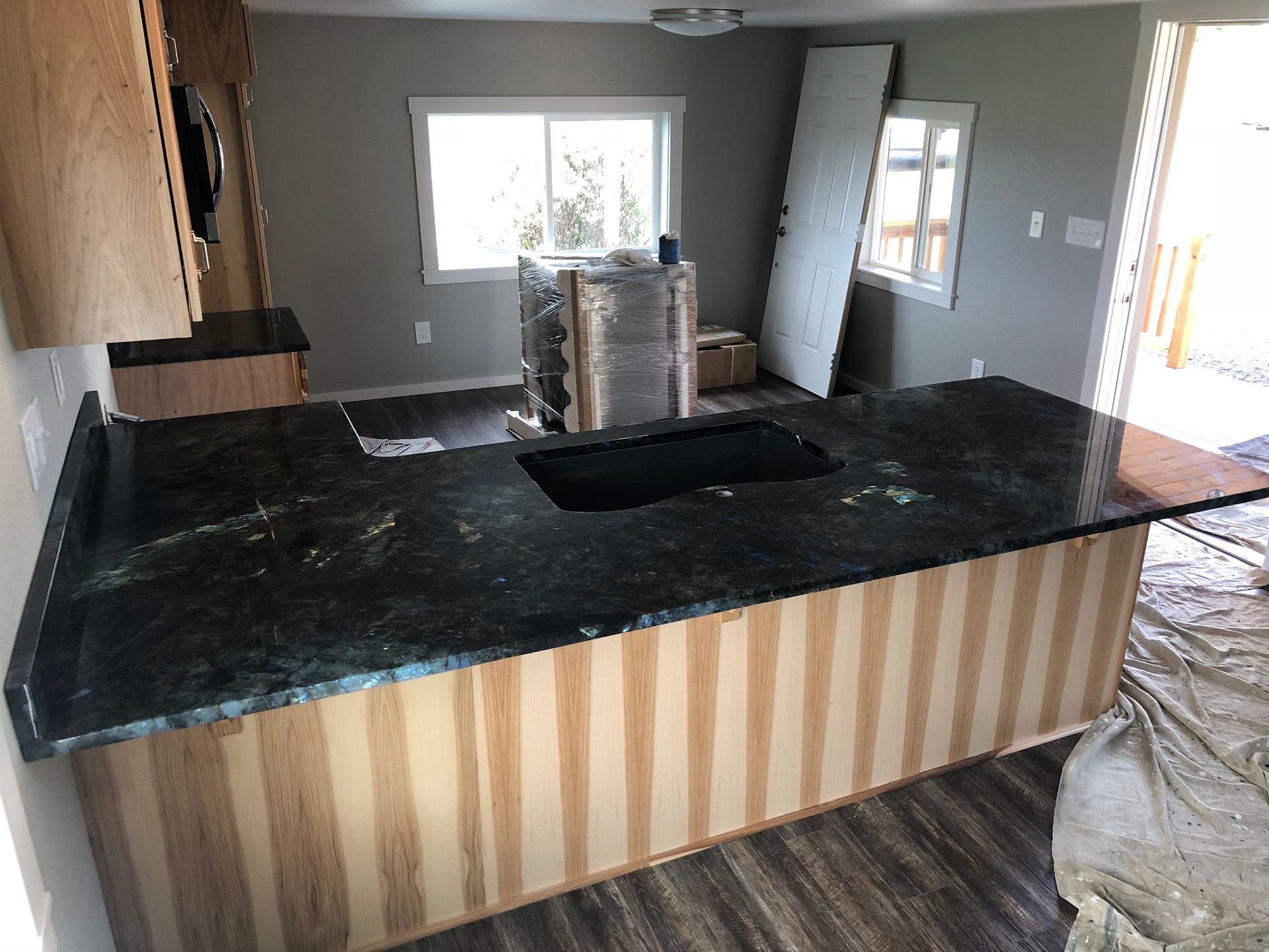 Partially finished kitchen with a granite island and stacked materials by the window