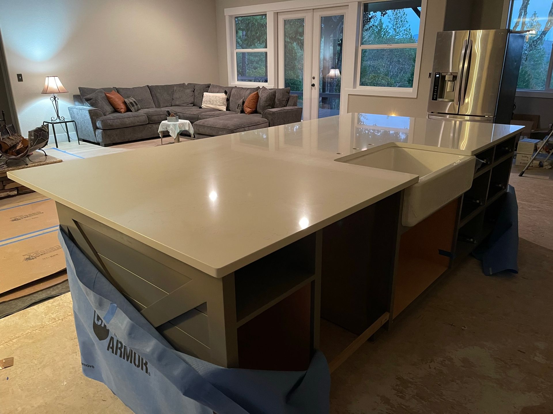 Modern kitchen island with light countertop; living room and windows visible in the background.