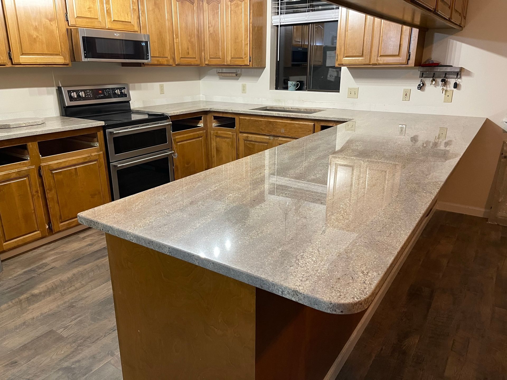 Modern kitchen with wooden cabinets, stainless steel appliances, and a large granite island countertop