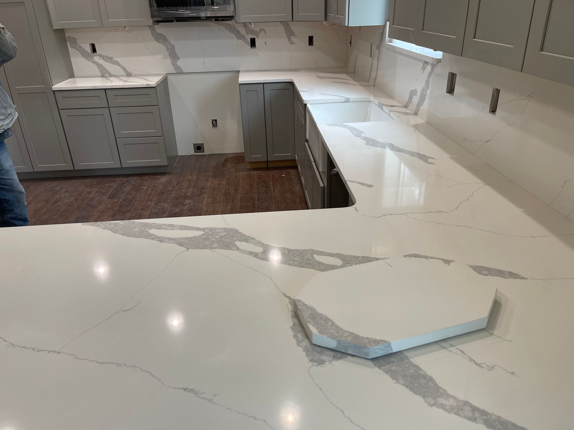 Kitchen with damaged white countertop and a broken cabinet panel on the floor