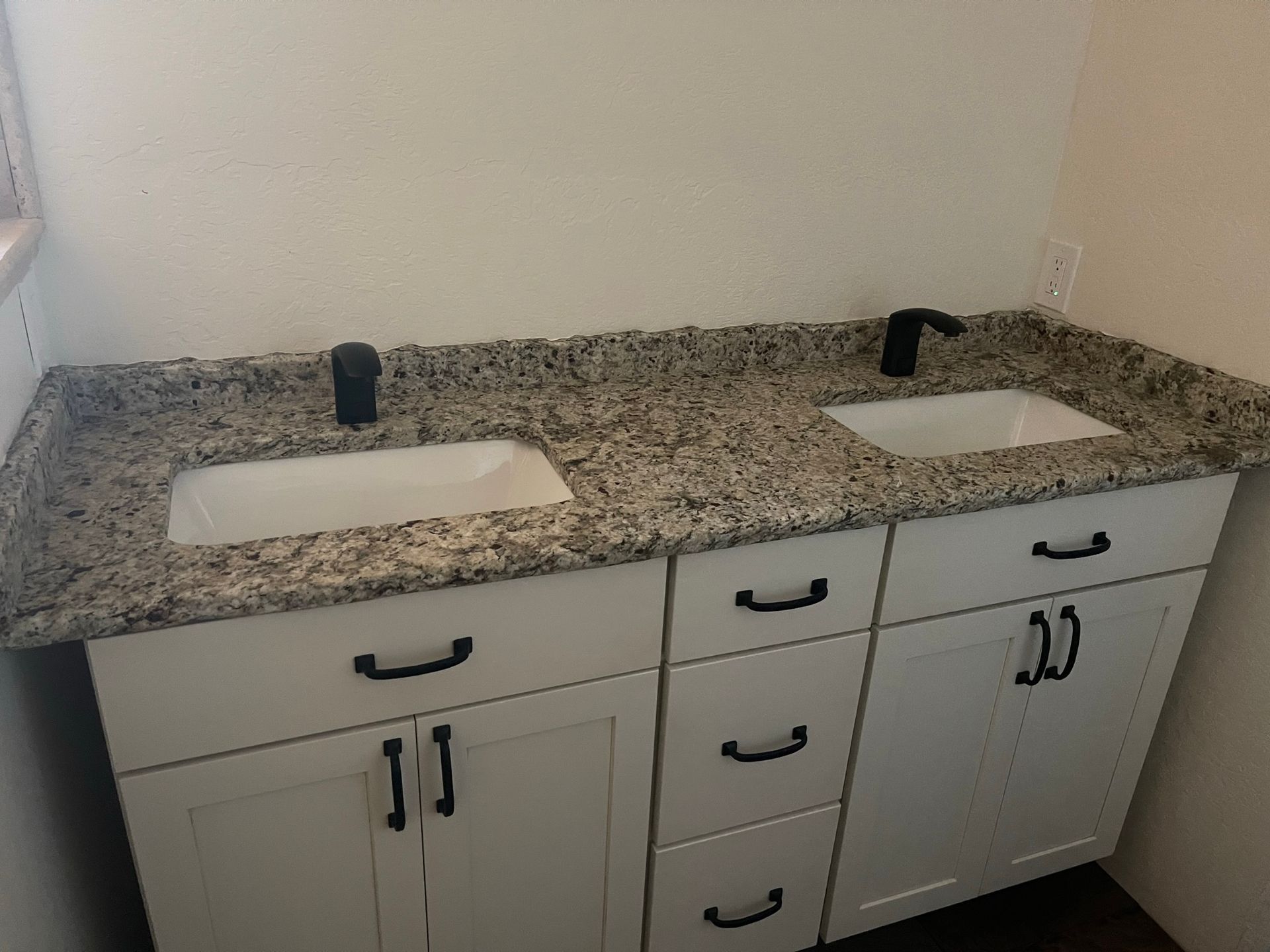 Double vanity with two white sinks, granite countertop, and white cabinets in a bathroom