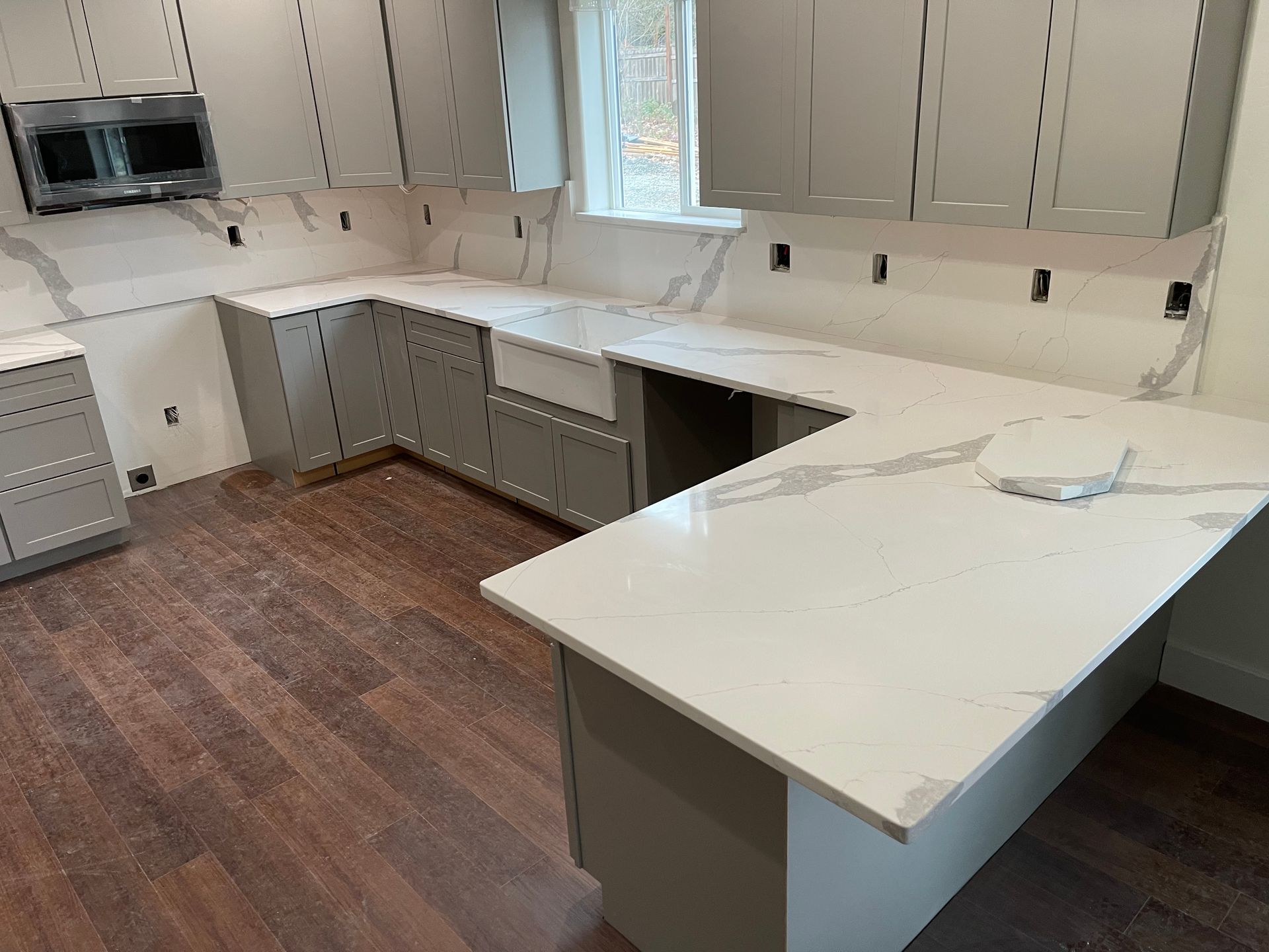 Modern kitchen with white cabinets, marble island, and wood floors