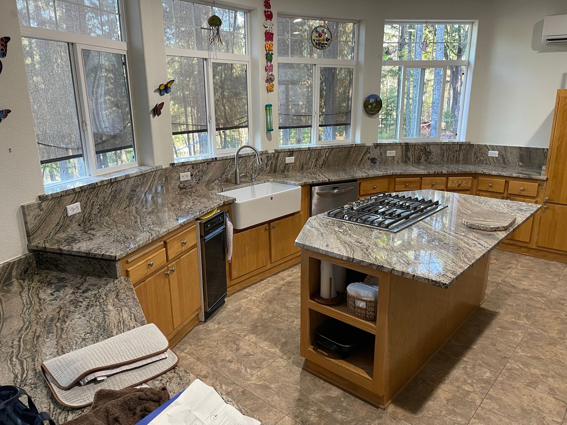 Bright kitchen with granite counters, central island, wood cabinets, and large windows.