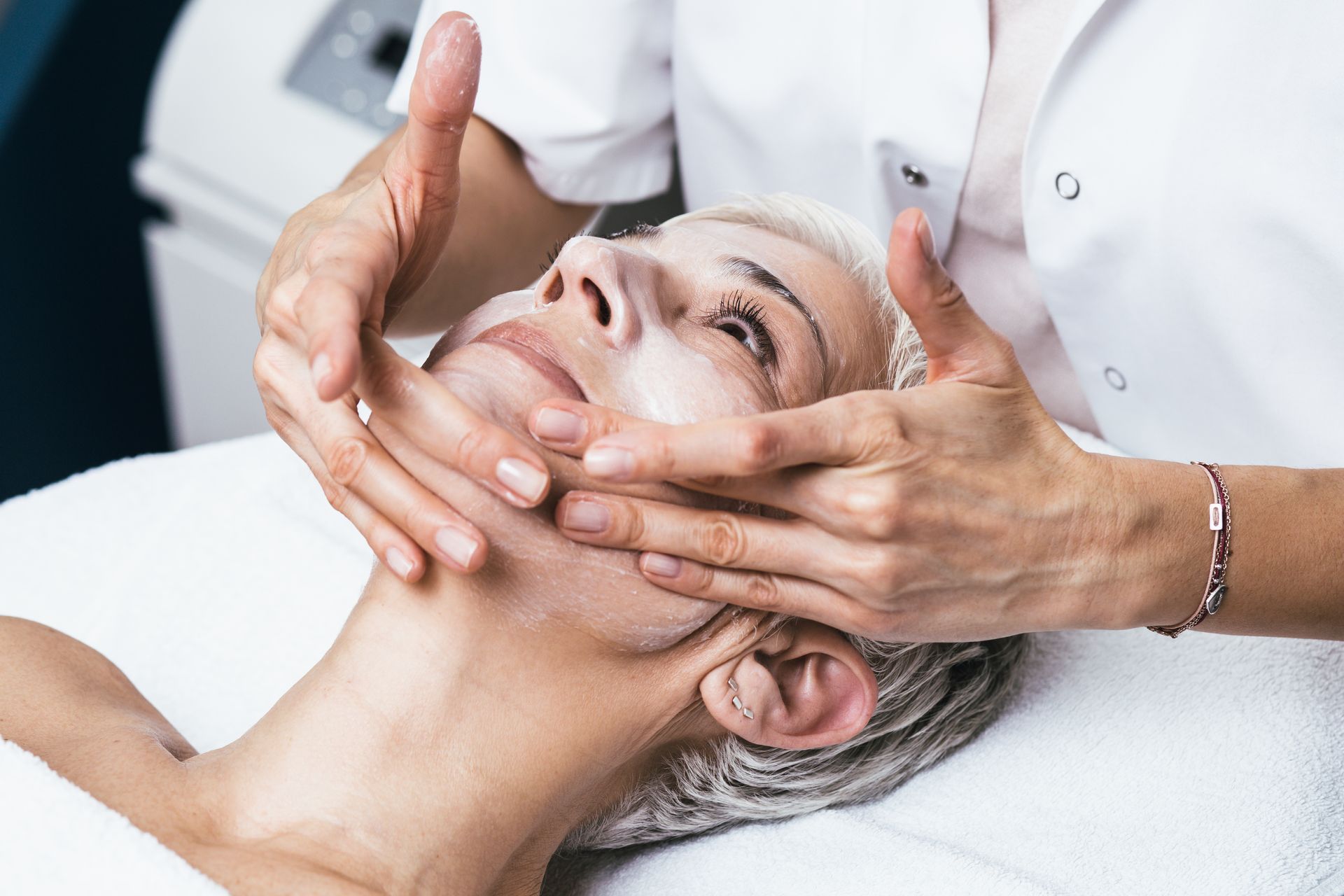 Facial massage in a spa, with hands gently lifting a woman’s face on a treatment table