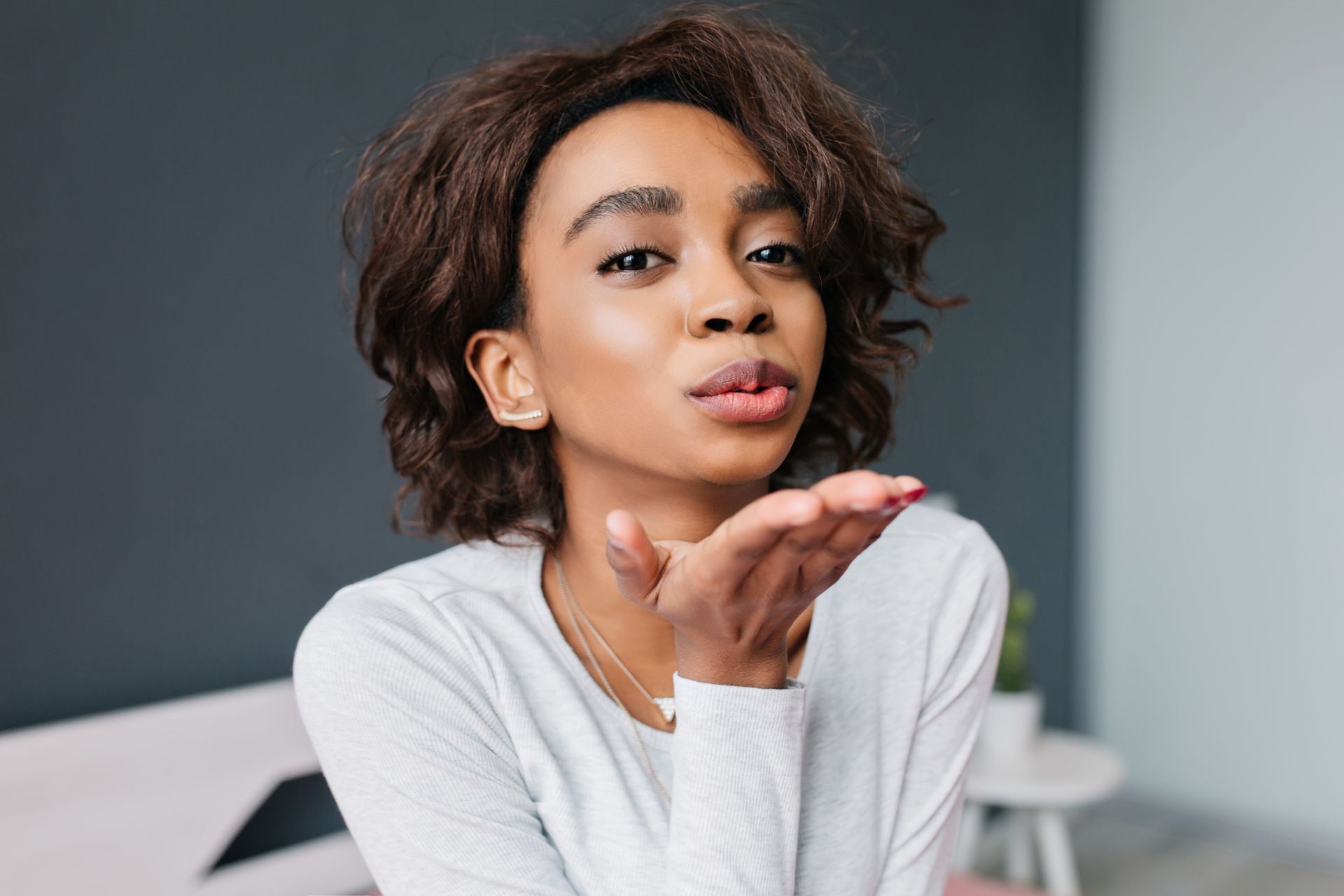 a woman is blowing a kiss with her hand .
