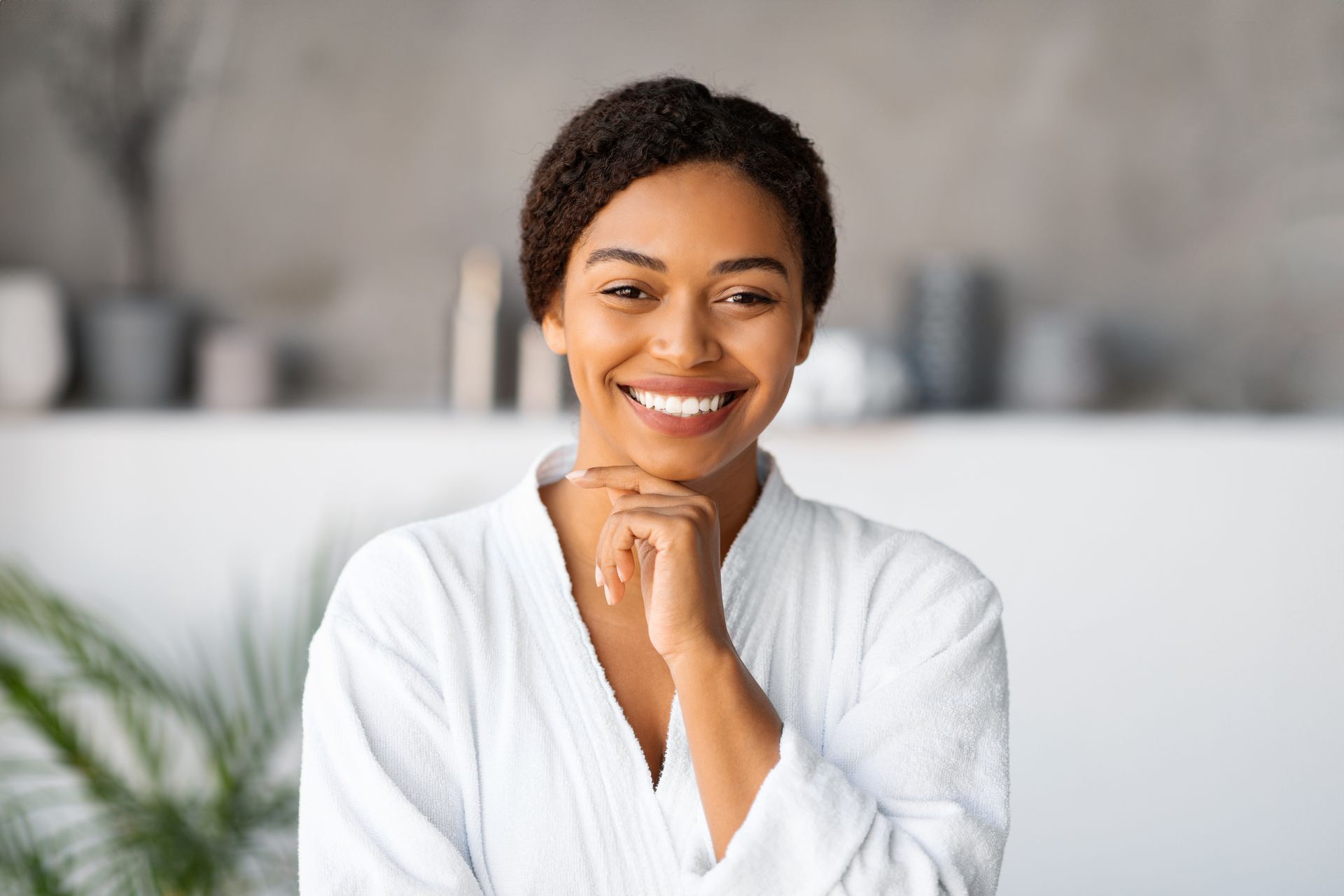 a woman in a bathrobe is smiling with her hand on her chin .