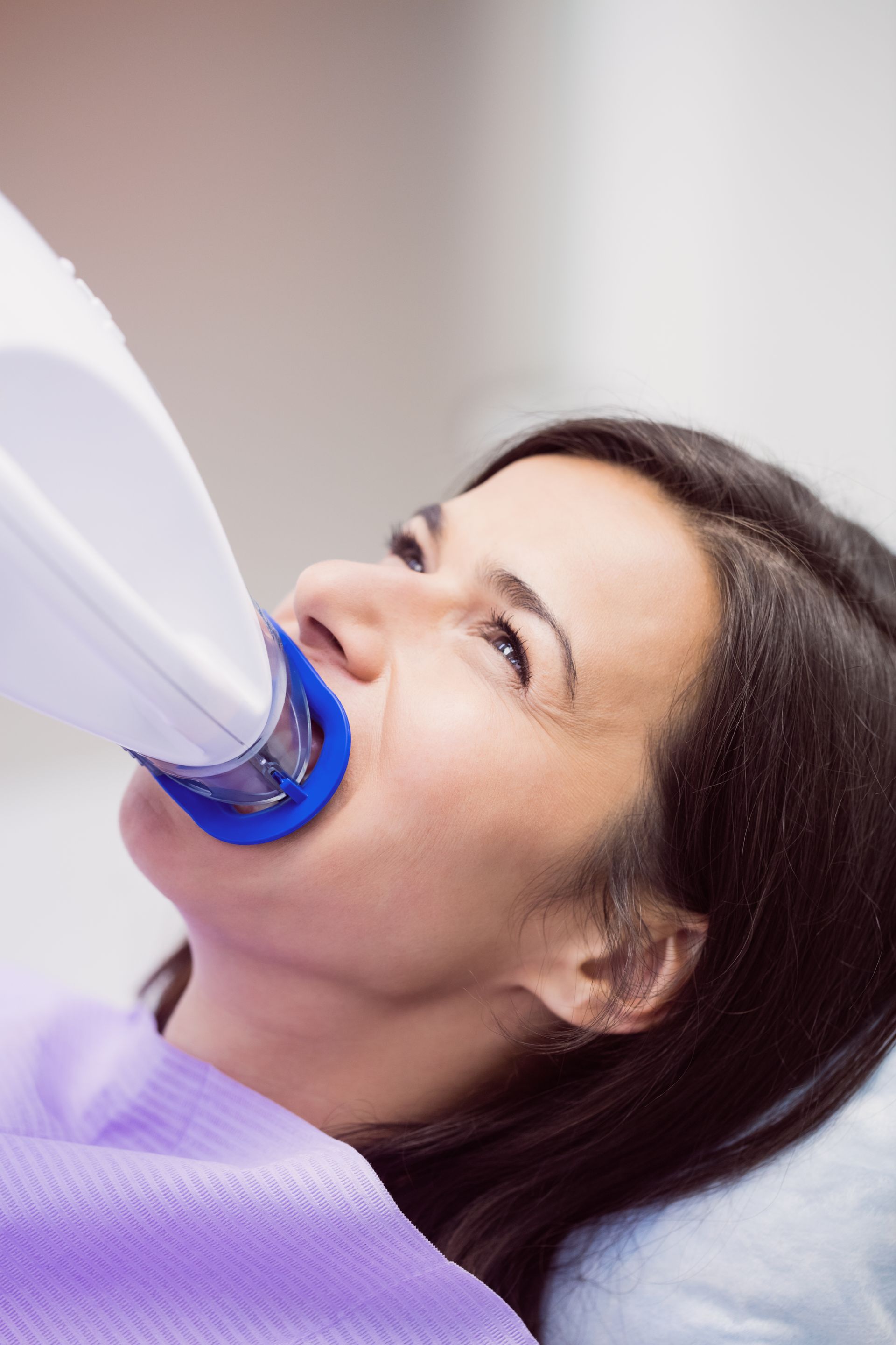 a woman is getting her teeth whitened in a dental office .
