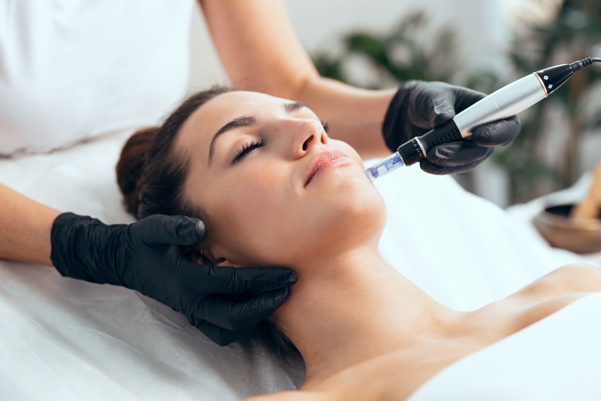 Cosmetic facial treatment with gloved hands using a syringe on a relaxed woman lying down