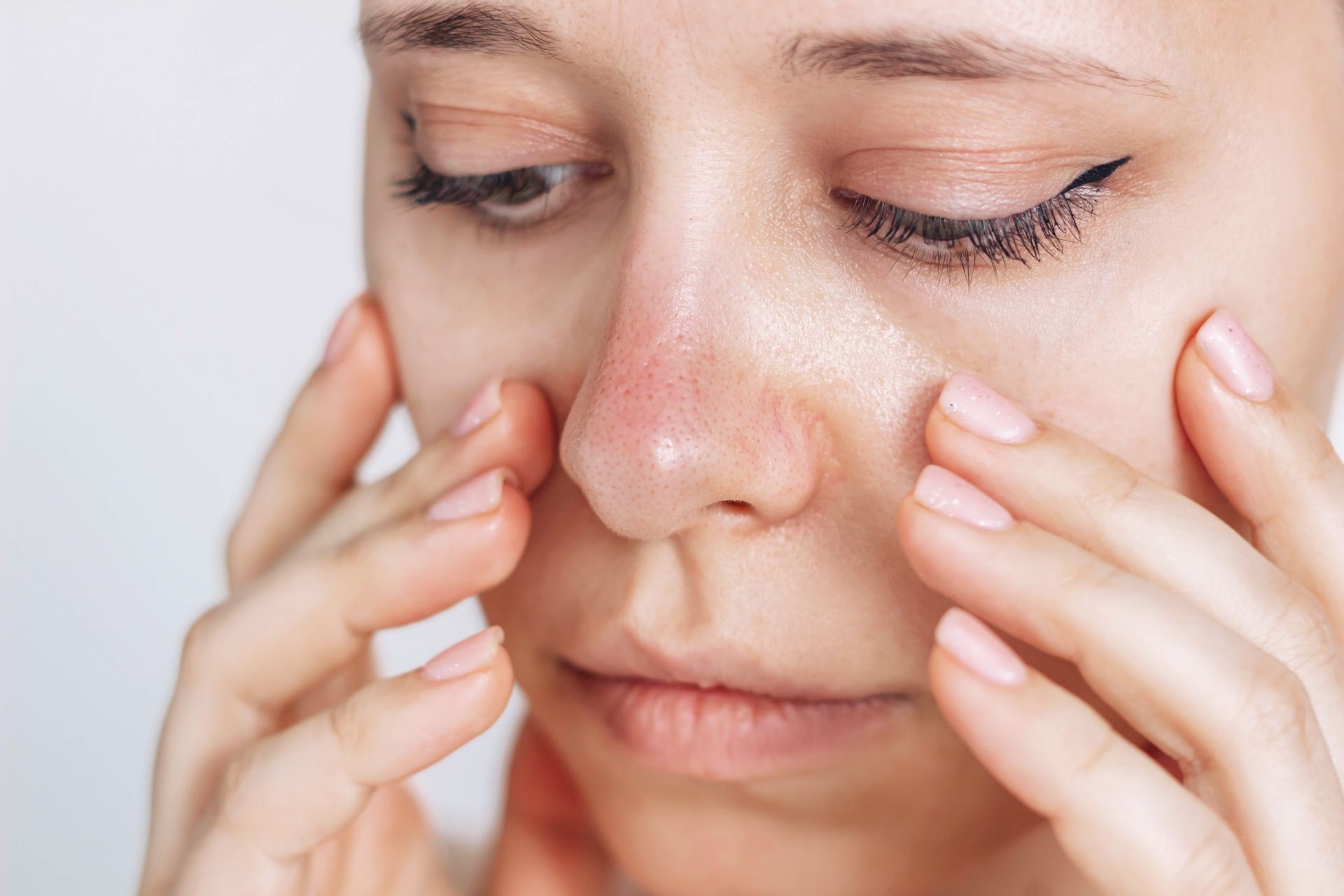 Woman touching face, nose is red. Close up view.