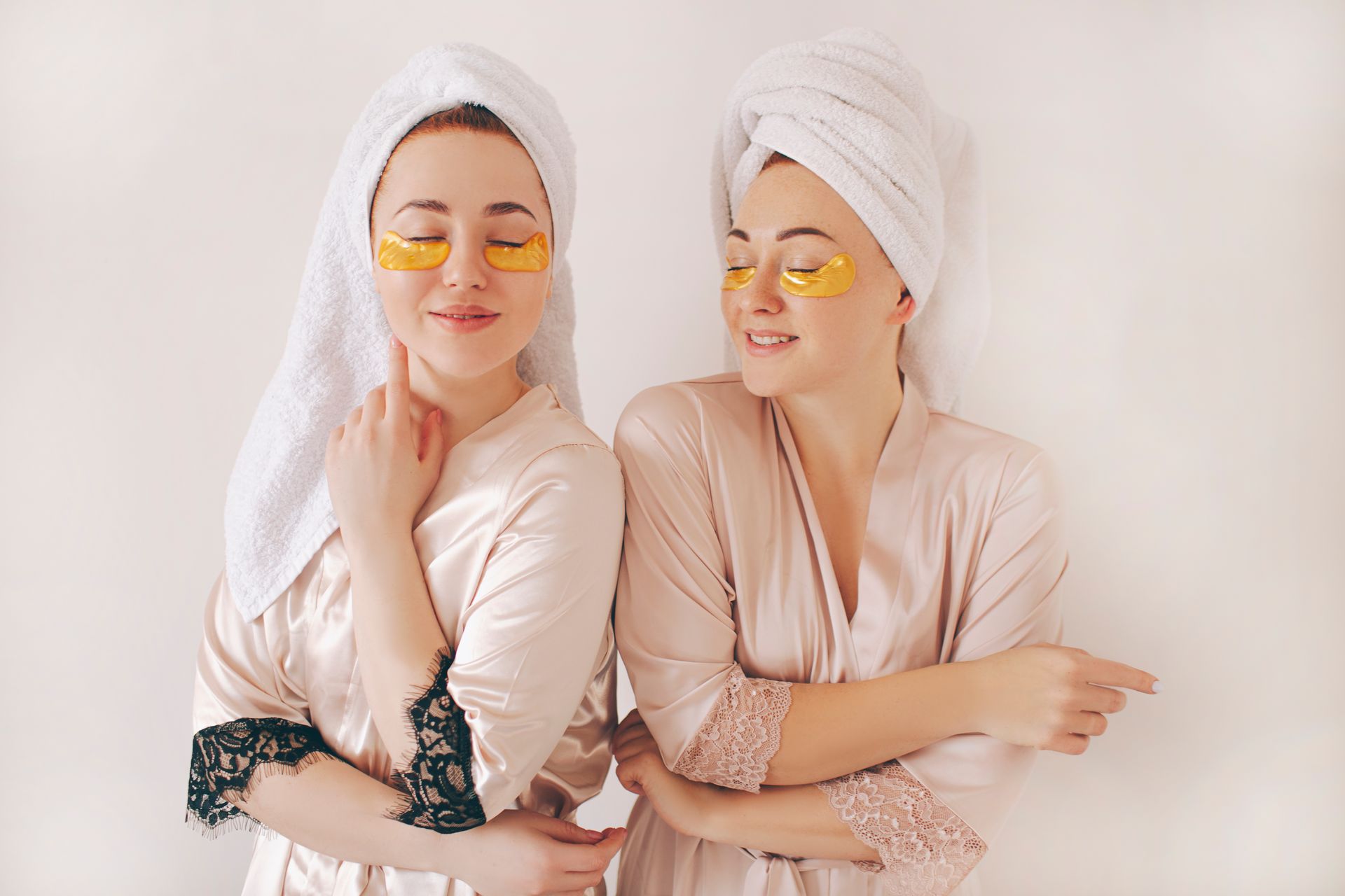Two women wearing eye patches and towels on their heads are standing next to each other.