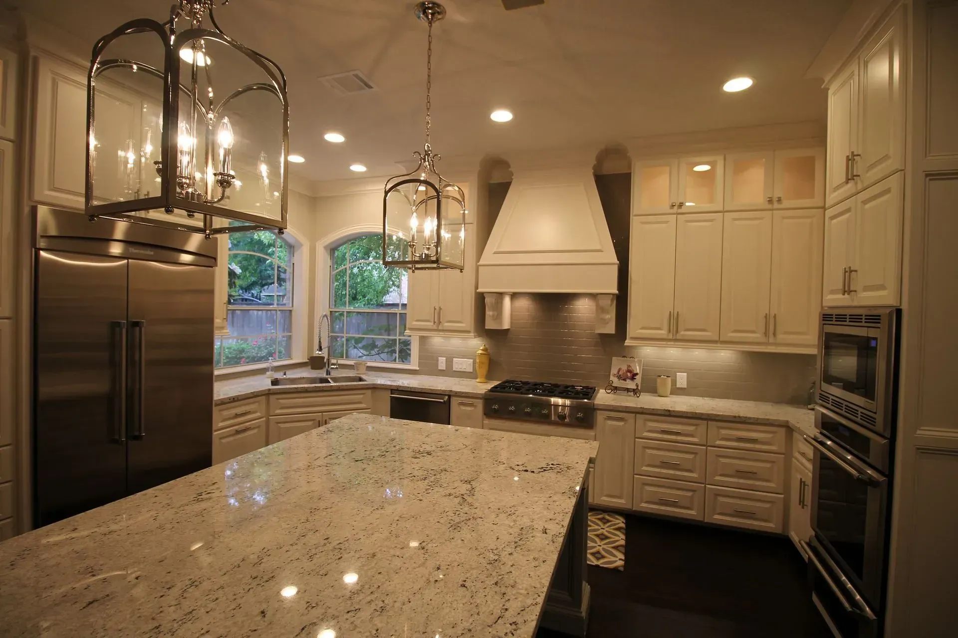 Modern kitchen with granite island, cream cabinets, stainless appliances, and pendant lights