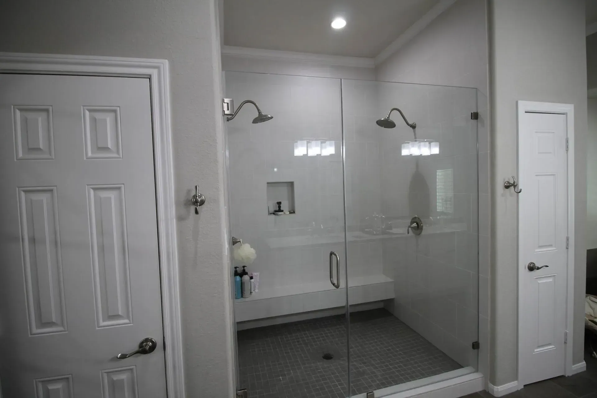 Small gray bathroom with a glass-enclosed shower, white vanity, and a closed door.