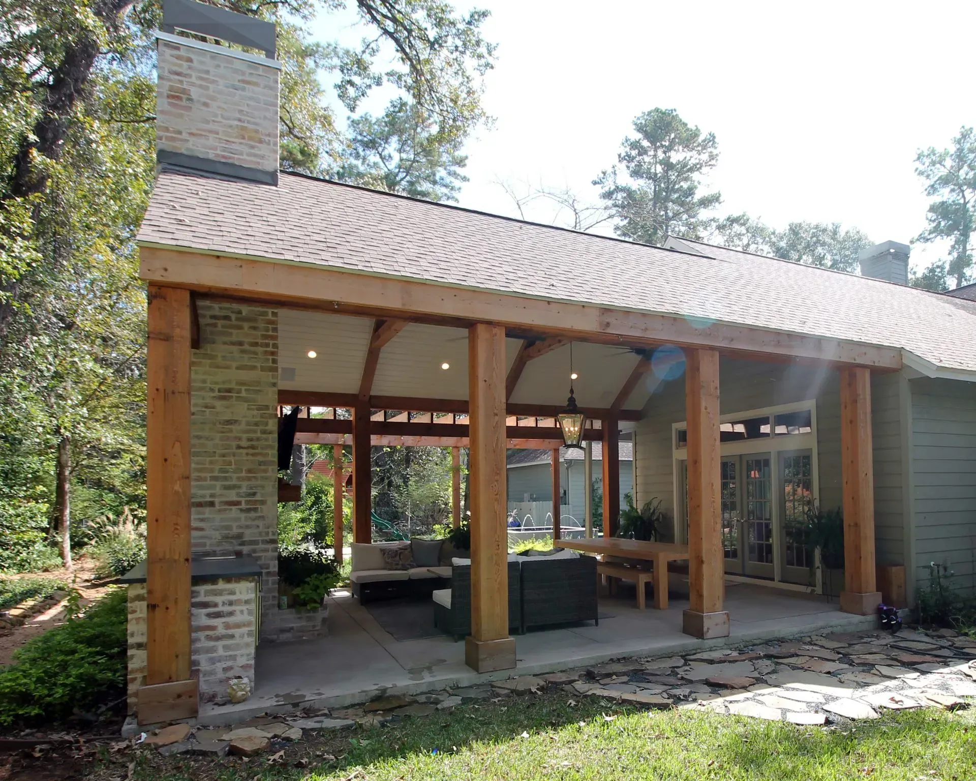Modern stone-and-wood pavilion with open seating in a wooded outdoor setting
