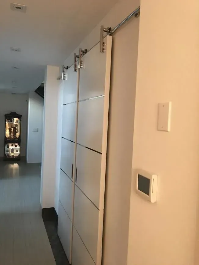 Hallway with white built-in cabinets and wall-mounted controls in a modern home
