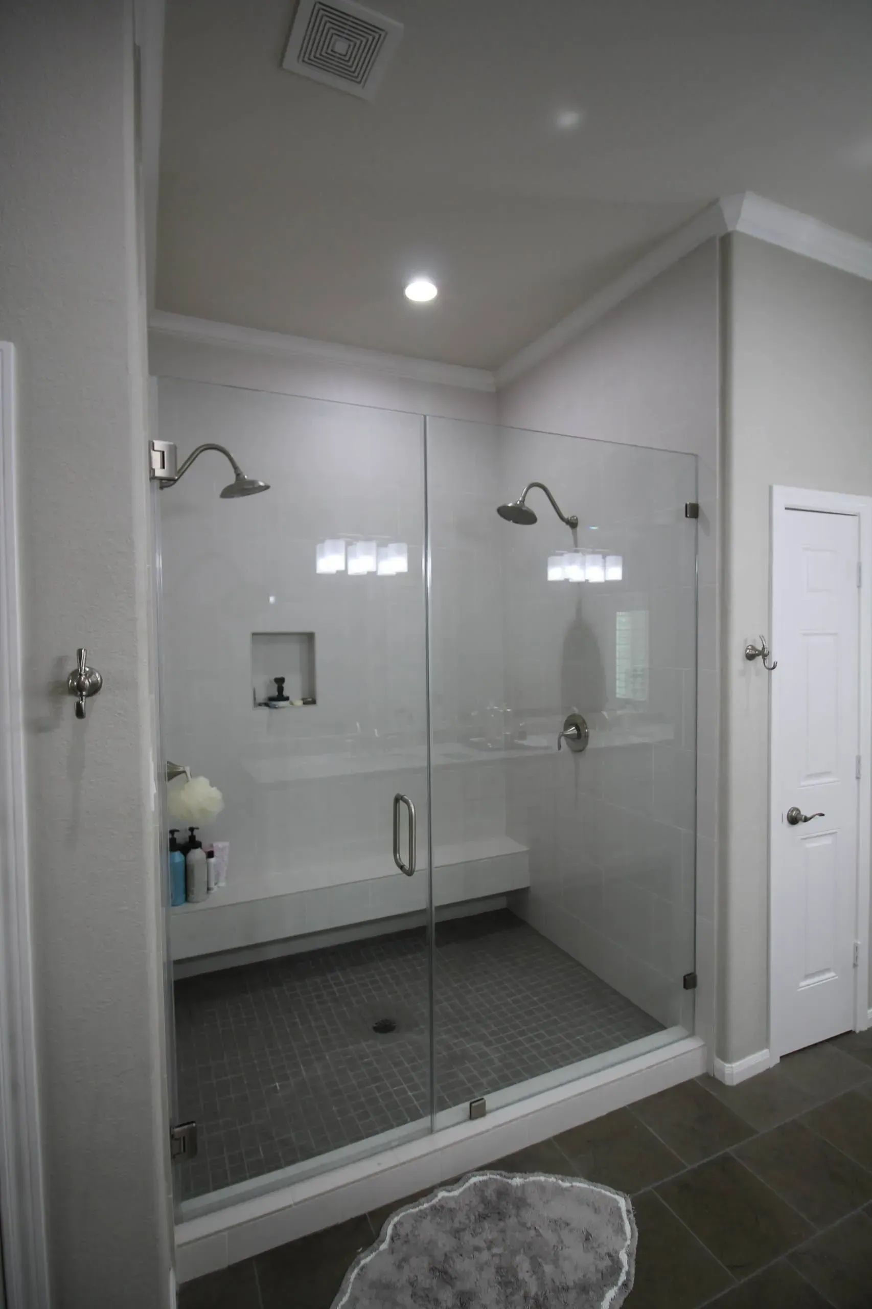 Modern bathroom with glass-enclosed shower, white tile, and dark floor tiles