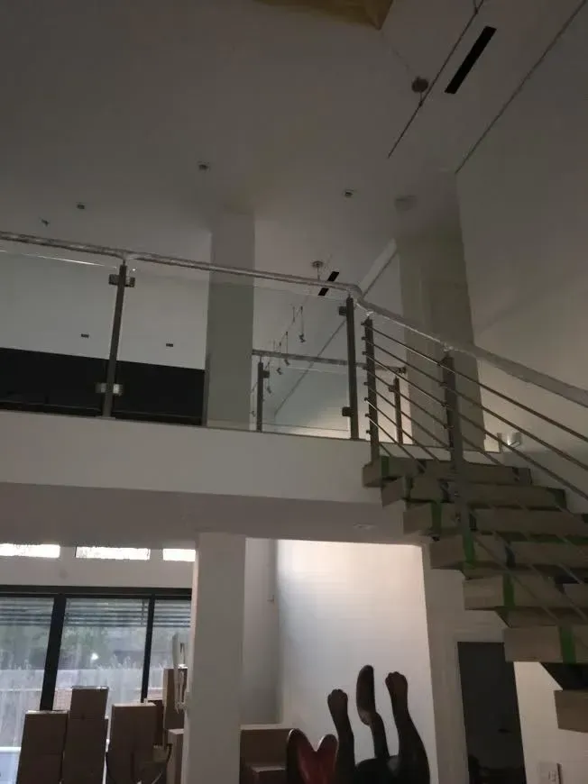 Bright modern interior with a staircase, glass railing, and large windows.