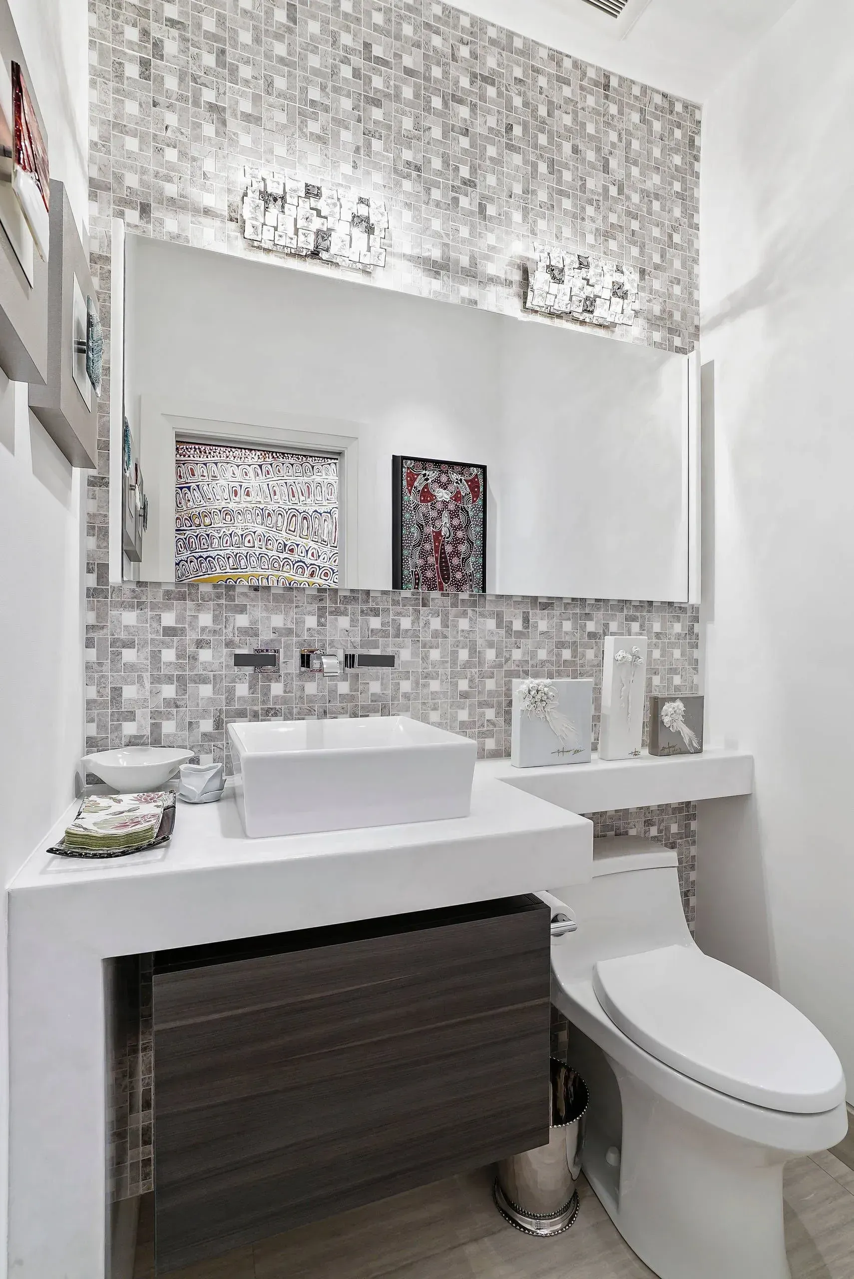Compact modern bathroom with white sink, toilet, mosaic tile walls, and mirrored cabinet