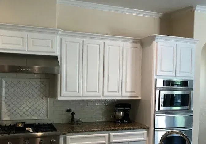 Modern kitchen with white cabinets, tiled backsplash, and built-in stainless steel oven and range.